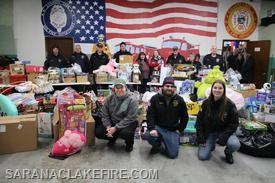 Volunteers take a moment to pose with the large pile of toys donated by our generous community.The